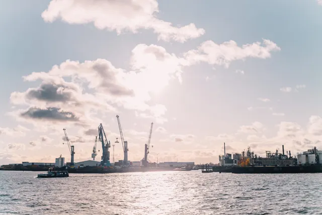 Hafenkräne und Industrieanlagen an der Elbe im Gegenlicht.