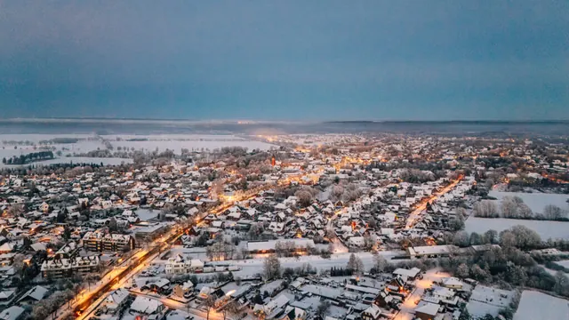 Luftbild von Tostedt im Schnee am Abend, beleuchtete Straßen.
